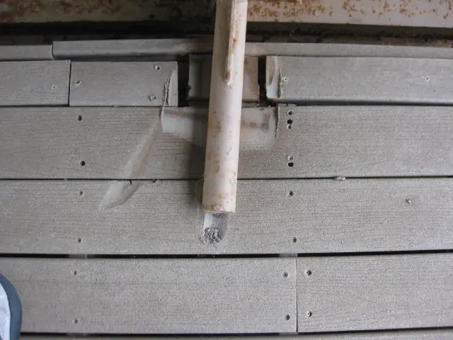 A loose pipe coming through horizontal siding at the side of a house