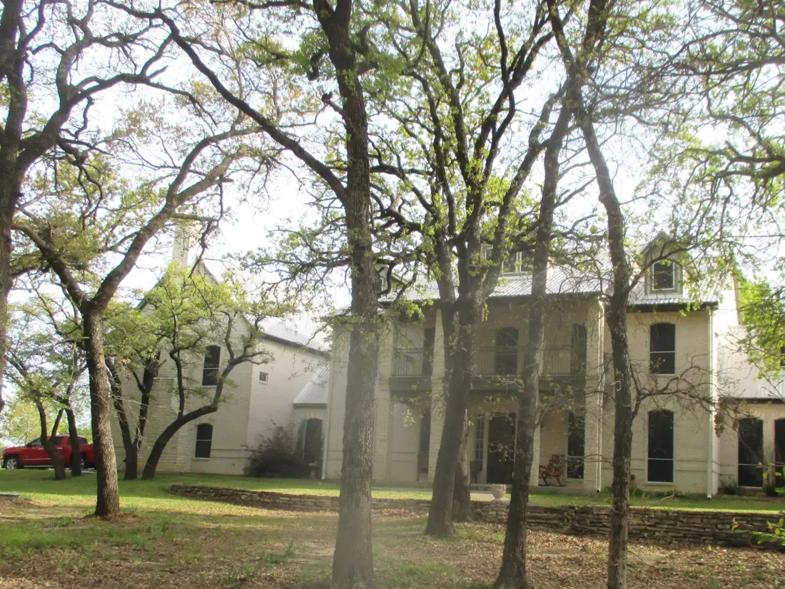A large two-storey stone house among live oaks, inspected by Alert Home Inspections