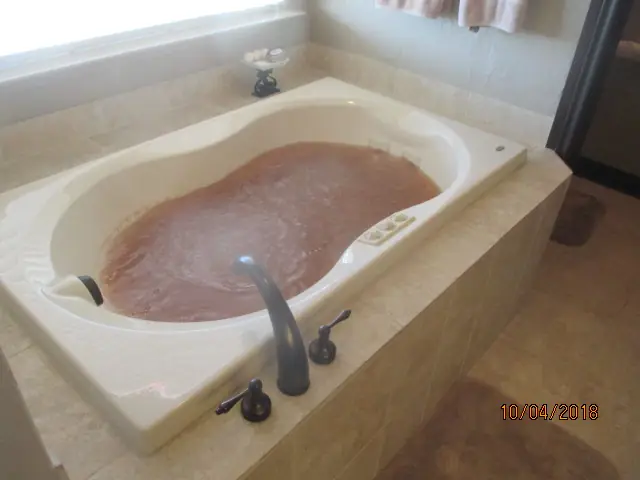 A jetted bathtub holding brown water, a finding on the hydro-massage line of the plumbing section