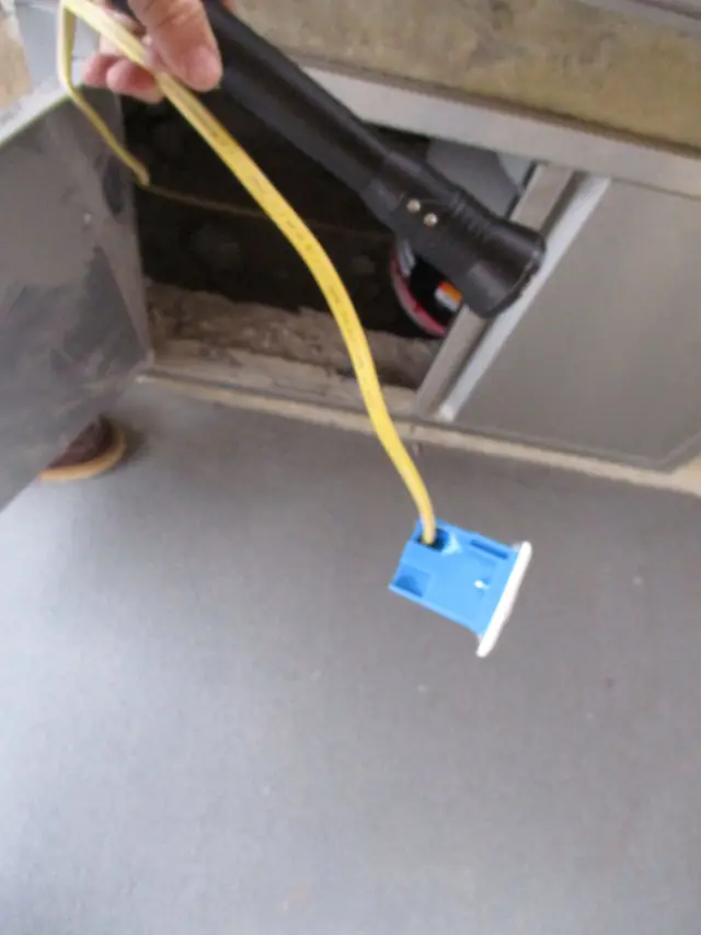Yellow wire running to a blue electrical box on a gray subfloor