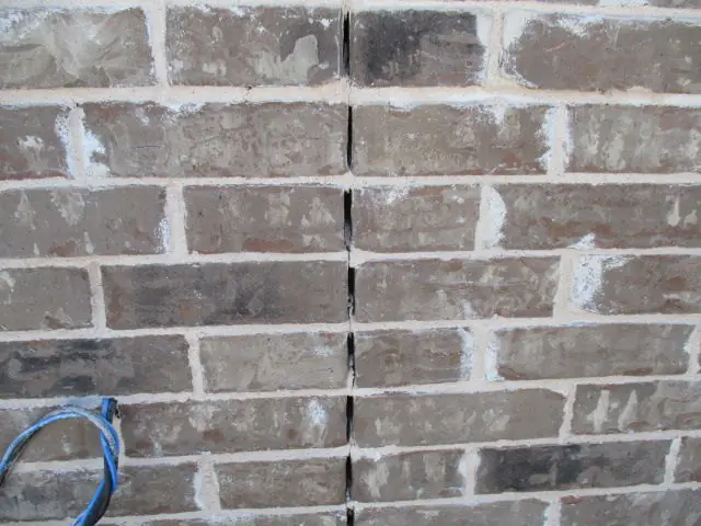 A vertical crack through a brick wall with missing mortar, found on an Alert inspection